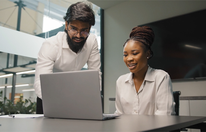 smiling colleagues in office working on laptop 