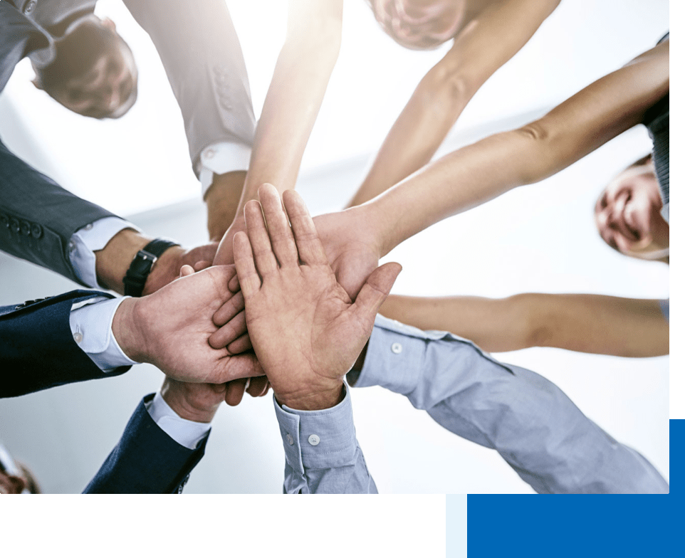Men and women in business attire putting their hands in for a team huddle