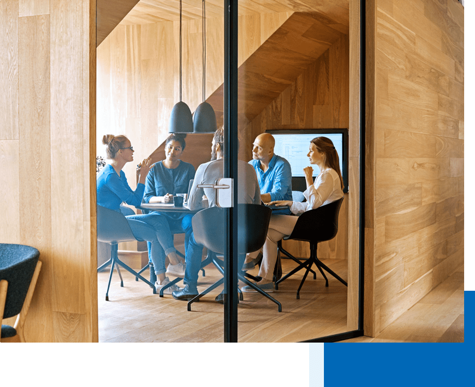 Men and women in business attire are having a meeting behind  a glass door