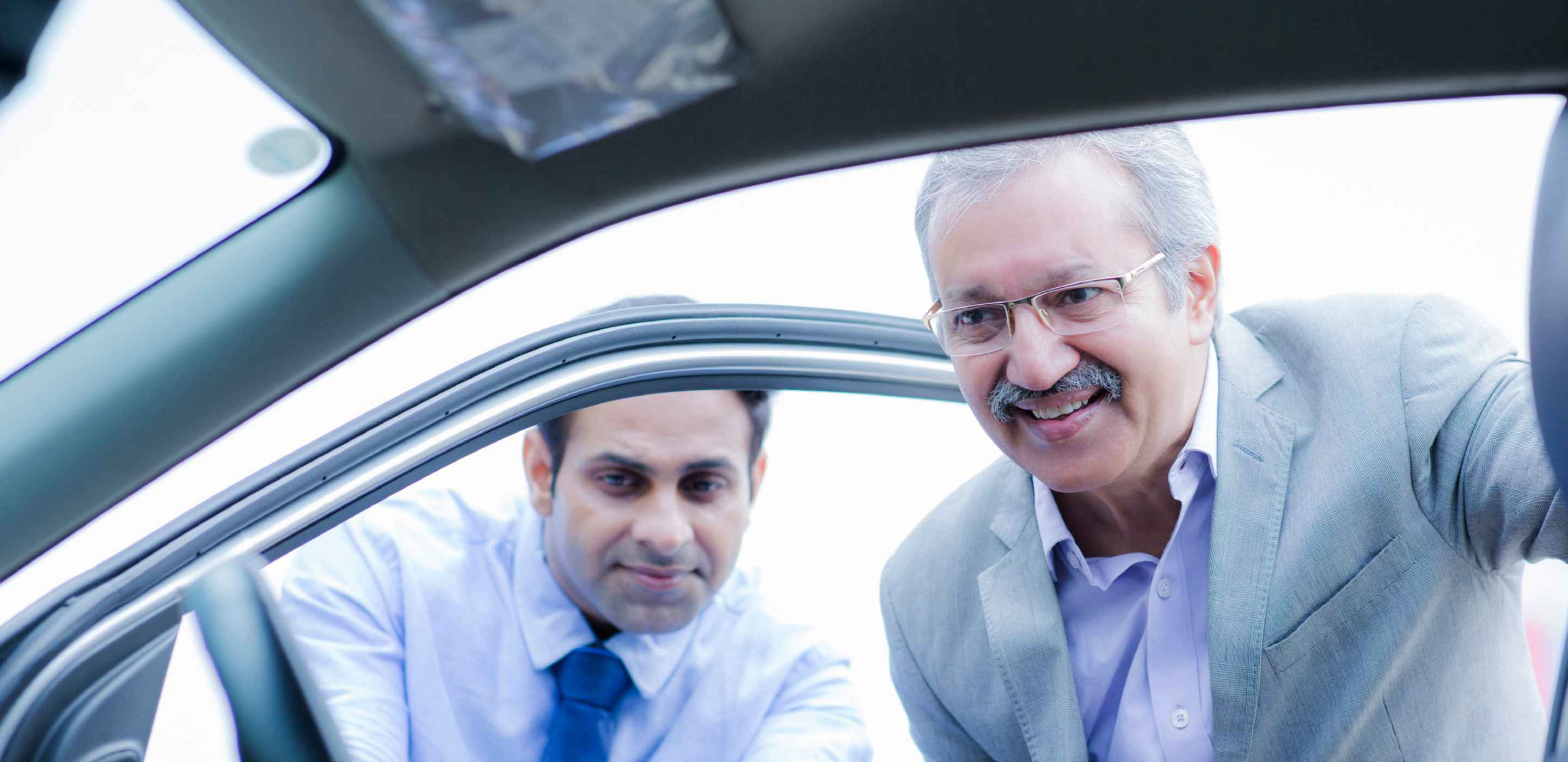 Two man looking at a car interior from outside
