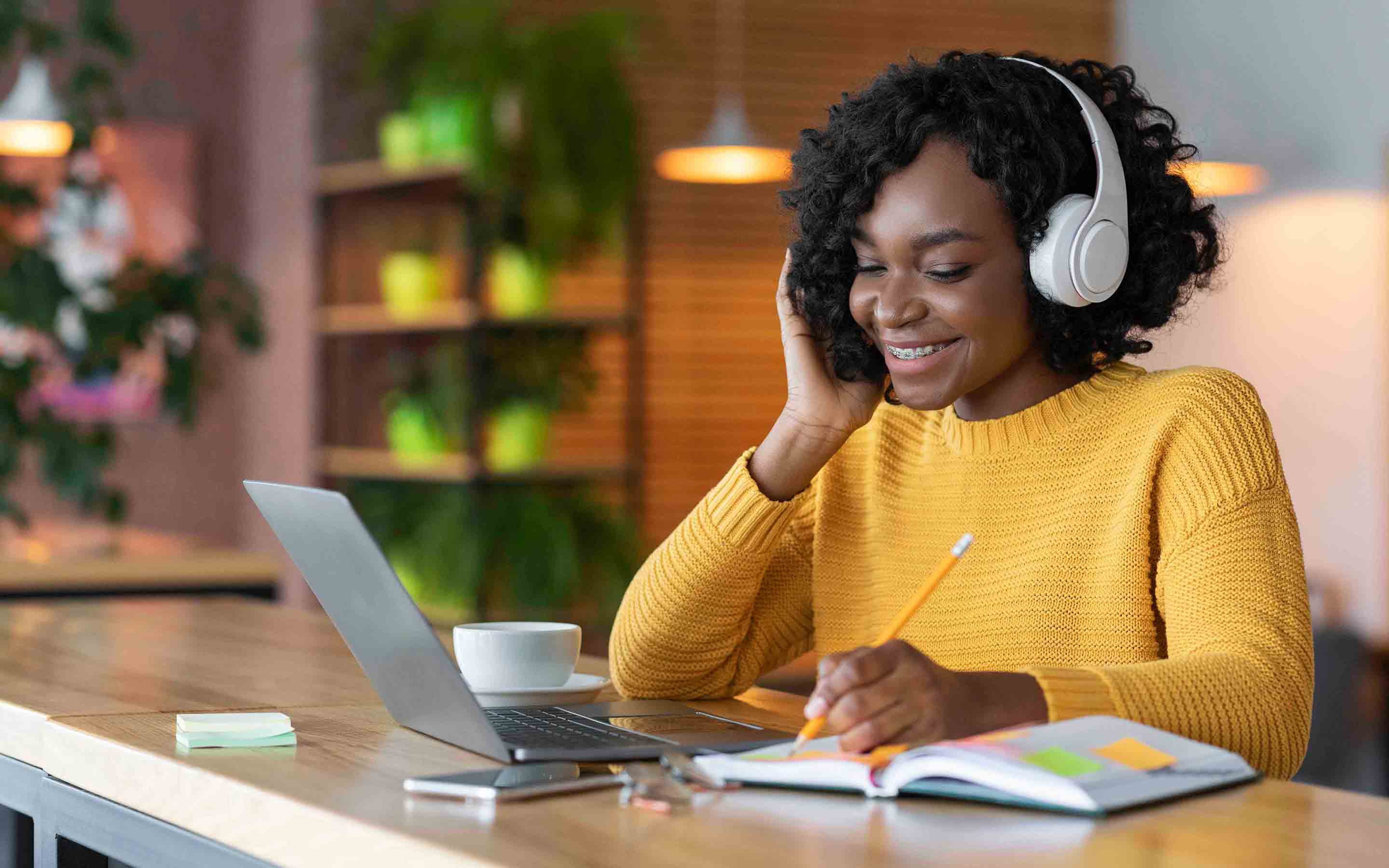 College student working at desk with headphones on