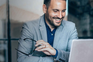 A man looking at a laptop screen with optic glasses on the hand