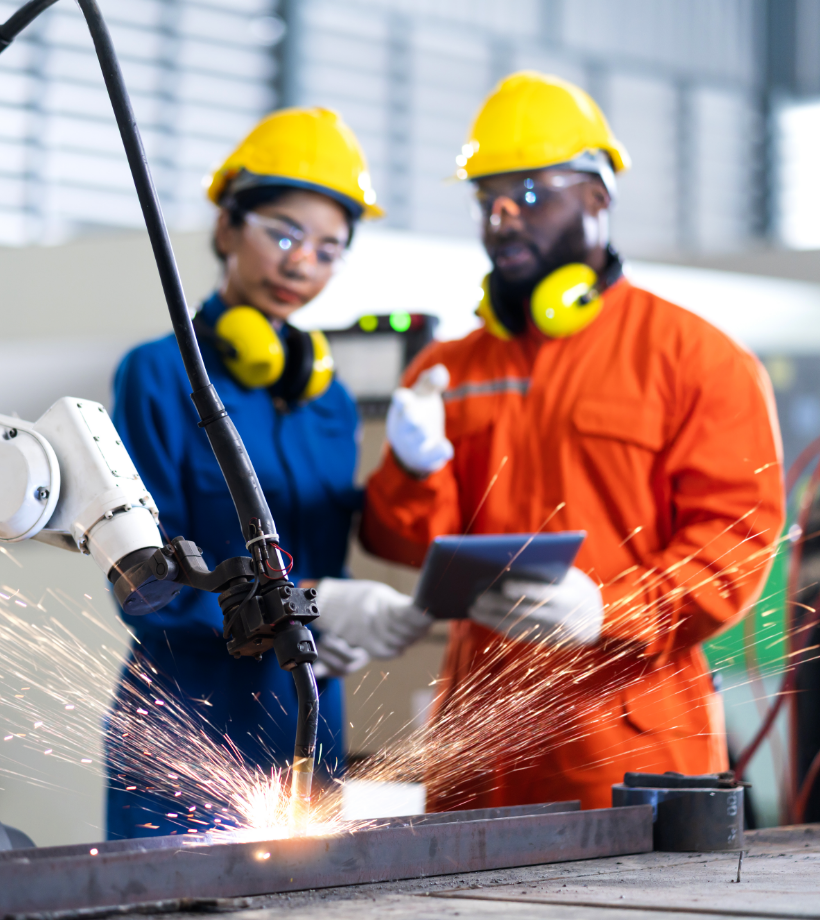 A woman and a man wearing protective gear watching a machine grinding