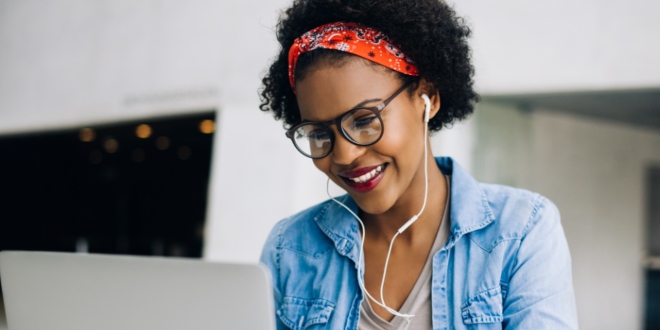 A woman sitting at her desk with earphones in