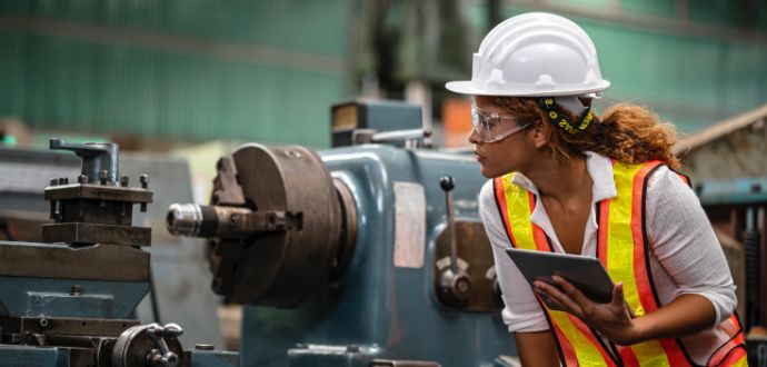 Woman wearing a hard-hat inspecting machinery