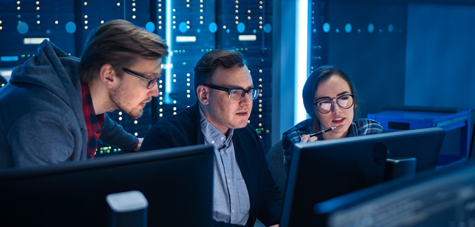 People in a server room looking at a monitor