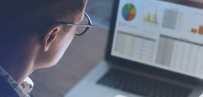 A person looking at a laptop with graphs on the screen