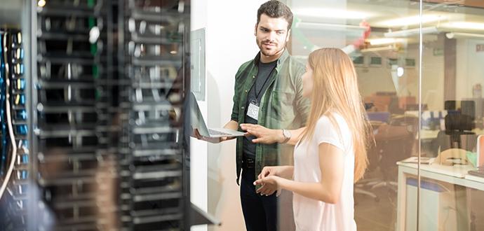 Two people standing next to a server and talking