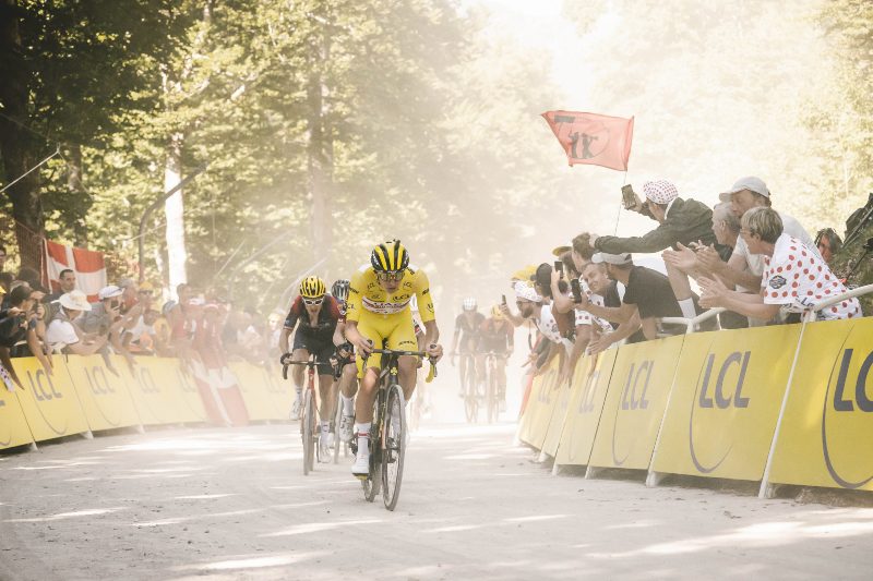Cyclist racing on a curved road with supporters on the sides