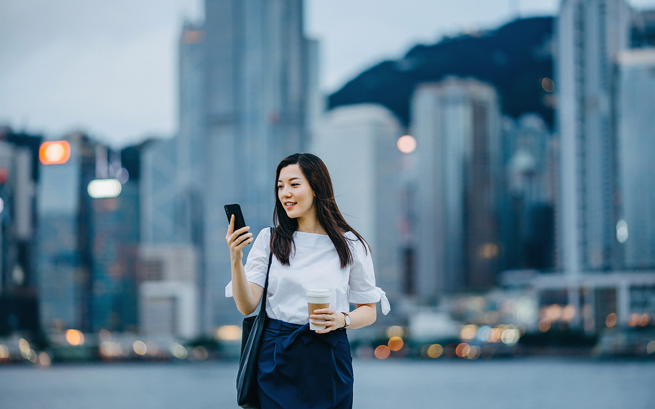 Woman with mobile phone walking on a city street